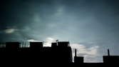 Time lapse clip - Moon and clouds behind house fronts